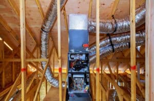 Ductwork installation by a local HVAC company in an attic, featuring an air handling unit and various ducts connected within the wooden framework.