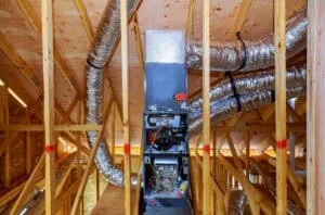 Ductwork installation by a local HVAC company in an attic, featuring an air handling unit and various ducts connected within the wooden framework.